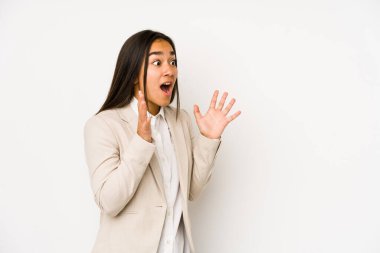 Beyaz arka planda izole edilmiş genç bir kadın yüksek sesle bağırıyor, gözleri açık ve elleri gergin tutuyor..