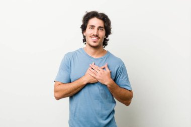 Beyaz bir geçmişi olan genç yakışıklı bir adam, dost canlısı bir ifadeye sahip, avuçlarını göğsüne bastırıyor. Aşk konsepti.