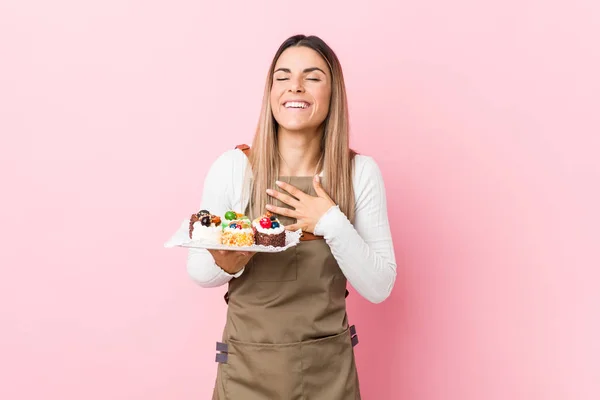 Young Baker Woman Holding Sweets Laughs Out Loudly Keeping Hand — Stock Photo, Image