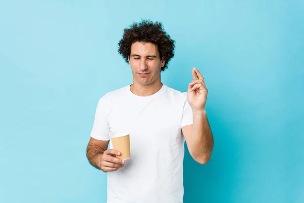 Jovem Caucasiano Encaracolado Homem Segurando Takeaway Café Cruzando Dedos Para — Fotografia de Stock