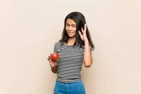 年轻的亚洲女人 手拿着苹果捂住耳朵 — 图库照片