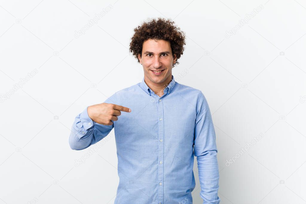 Young curly mature man wearing an elegant shirt person pointing by hand to a shirt copy space, proud and confident