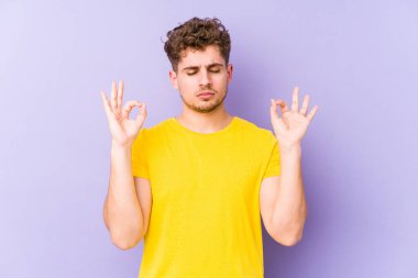 Sarışın, kıvırcık saçlı, beyaz tenli genç adam sıkı çalışma gününden sonra dinleniyor. Yoga yapıyor..