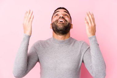 Pembe arka planda genç bir latin adam gökyüzüne haykırıyor, bakıyor, hayal kırıklığına uğruyor..