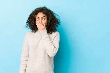 Genç Afro-Amerikan kıvırcık saçlı kadın. Düşünceli bir şekilde fotokopi odasına bakıyor. Ağzını eliyle kapatıyor..