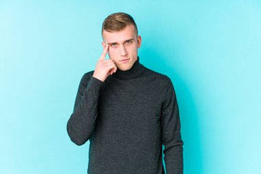 Mavi arka planda genç beyaz bir adam parmağıyla tapınağı işaret ediyor, düşünüyor ve bir göreve odaklanıyor..