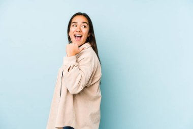 Genç bir kadın mavi arka plan noktalarında izole edilmiş, başparmak uzakta, gülüyor ve kaygısız..