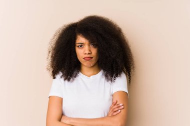 Afro-Amerikalı genç bir kadın hoşnutsuzca kaşlarını çatıyor, kollarını kavuşturuyor..
