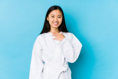 Young chinese woman practicing karate isolated laughs out loudly keeping hand on chest.