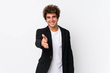 Beyaz arka planda beyaz tenli genç beyaz bir iş adamı kameraya doğru elini uzatarak selam veriyor..