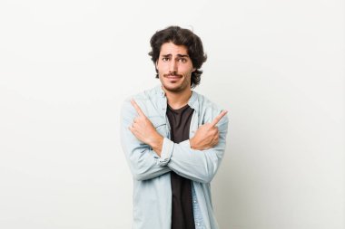 Beyaz bir arka plan noktasında genç yakışıklı adam, iki seçenek arasında seçim yapmaya çalışıyor..