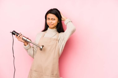 Genç Çinli bir kadın mikser tutuyor. Bir dedikoduyu dinlemeye çalışıyor..