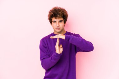 Pembe arka planda genç beyaz bir adam tecrit edilmiş bir jest yapıyor..