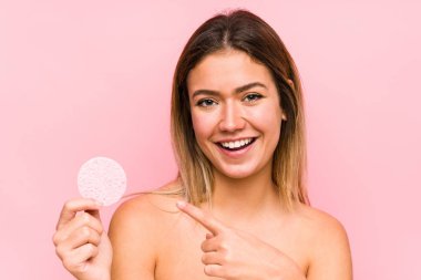 Yüz diski tutan beyaz bir kadın izole edilmiş. Gülümsüyor ve işaret parmağıyla işaret ediyor..