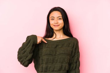 Pembe arka planda yaşayan genç Çinli bir kadın tişört fotokopisini elle gösteriyor, gururlu ve kendinden emin.