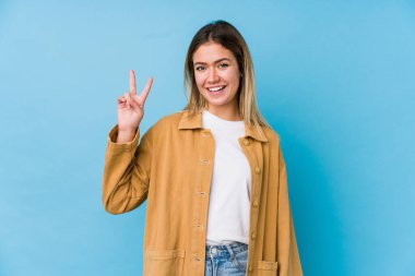 Genç beyaz kadın zafer işareti gösteriyor ve gülümsüyor..