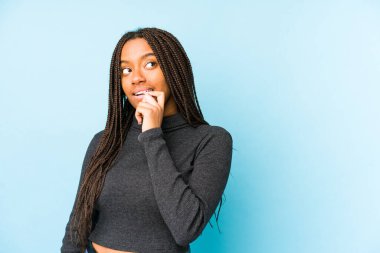 Mavi arka planda izole edilmiş genç Afrikalı Amerikalı kadın rahatça fotokopi odasına bakan bir şey düşünüyor..
