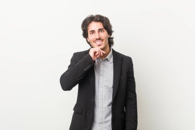 Beyaz bir geçmişi olan genç bir iş adamı mutlu ve kendinden emin gülümsüyor, elleriyle çenesine dokunuyor..