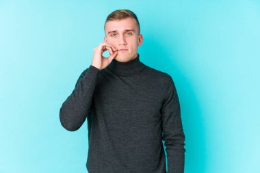 Mavi arka planda, dudakları dudaklarında, sır saklayan genç beyaz bir adam..