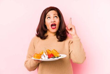 Orta yaşlı Latin bir kadın, elinde waffle tutuyordu. Ağzı açık, üst tarafı gösteriyordu..