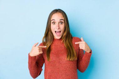 Kafkasyalı bir kadın yalnız poz veriyor. Parmakla işaret ediyor, gülümsüyor..