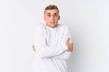 Beyaz arka planda beyaz tenli genç bir adam düşük ateş ya da hastalık yüzünden soğuyor..