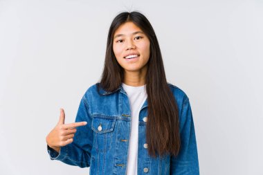Young asian woman person pointing by hand to a shirt copy space, proud and confident
