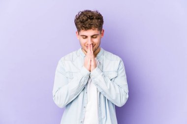 Sarışın, kıvırcık saçlı, beyaz tenli bir adam. El ele tutuşup dua ediyor. Kendine güveniyor..