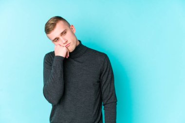 Mavi arka planda, üzgün ve dalgın hisseden, fotokopi alanına bakan genç beyaz bir adam..