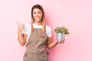 Genç bahçıvan beyaz kadın kendini izole edip gülümsedi ve başparmağını kaldırdı.