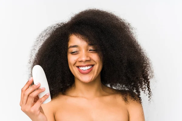 Mujer Afro Joven Sosteniendo Una Crema Hidratante Aislada Sonriendo Confiada — Foto de Stock