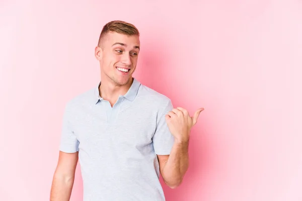 Young Caucasian Man Isolated Points Thumb Finger Away Laughing Carefree — Stock Photo, Image