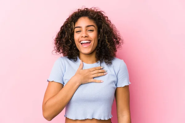 ピンクの背景に対する若いアフリカ系アメリカ人女性は 胸に手をつないで大声で笑う — ストック写真