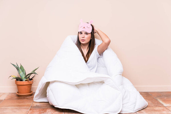 Young caucasian woman resting with a quilt being shocked, she has remembered important meeting.