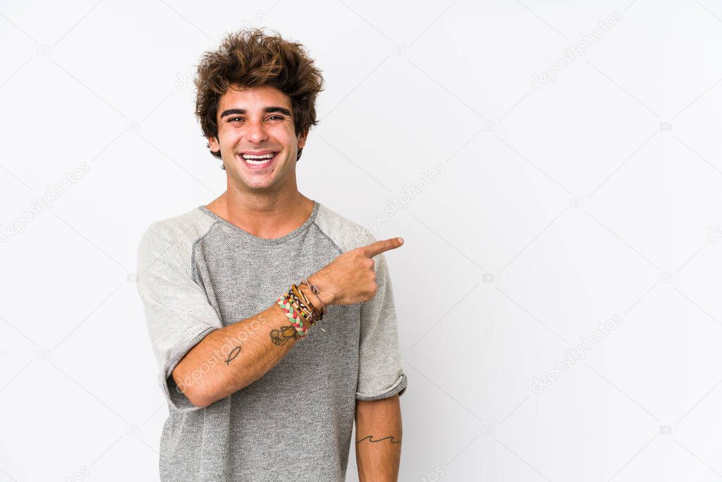 Young caucasian man against a white background isolated smiling and pointing aside, showing something at blank space.