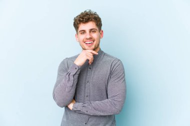 Sarışın, kıvırcık saçlı, soyutlanmış, mutlu ve kendinden emin, çenesine elinle dokunan beyaz bir adam..