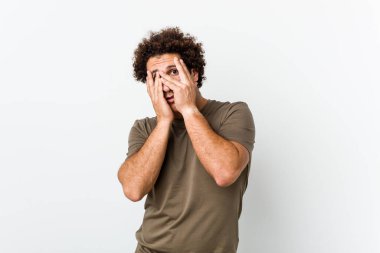 Mature handsome man isolated blink through fingers frightened and nervous.