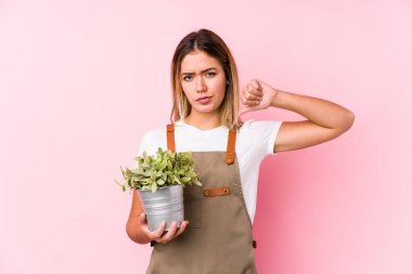 Pembe arka planda genç beyaz bahçıvan kadın kendini gururlu ve kendinden emin hissediyor..