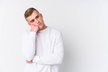 Beyaz arka planda üzgün ve dalgın hisseden genç beyaz bir adam fotokopi alanına bakıyor..