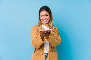 Beyaz bir kadın elinde avuç içi bir şeyle kameraya sunuyor..