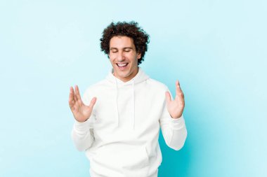 Young sporty man against a blue background joyful laughing a lot. Happiness concept.