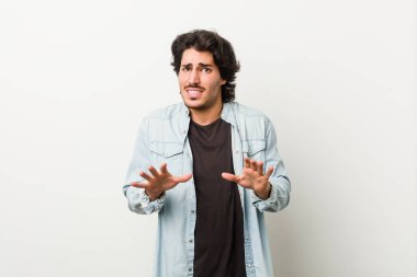 Young handsome man against a white background rejecting someone showing a gesture of disgust.