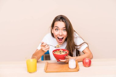 Genç beyaz kadın kahvaltı yapıyor.