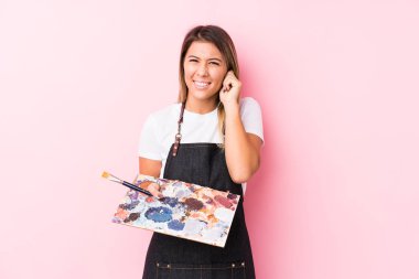 Young artist caucasian woman holding a palett isolated covering ears with hands.