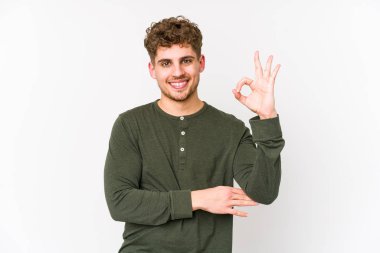 Sarışın, kıvırcık saçlı, beyaz tenli bir adam göz kırpıyor ve elinde iyi bir jest tutuyor..