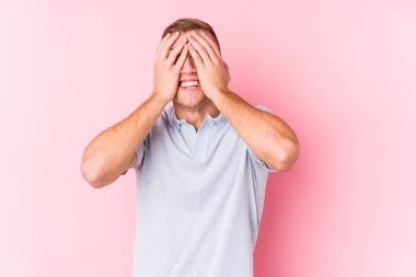 Young caucasian man isolated covers eyes with hands, smiles broadly waiting for a surprise.