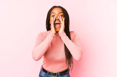 Genç Afrikalı Amerikalı bir kadın pembe bir arka planda izole edilmiş ve heyecanlı bir şekilde bağırıyor..