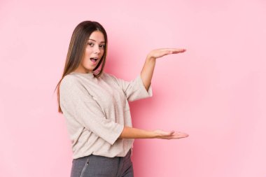 Kafkasyalı genç bir kadın yalnız poz veriyor. Şok olmuş ve hayrete düşmüş. Ellerinin arasında bir kopya alanı tutuyor..