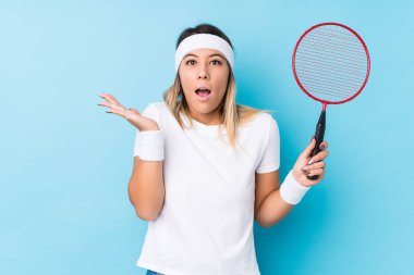 Young caucasian woman playing badminton isolated surprised and shocked.