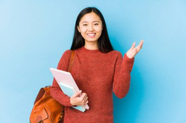 Young chinese student woman isolated receiving a pleasant surprise, excited and raising hands.